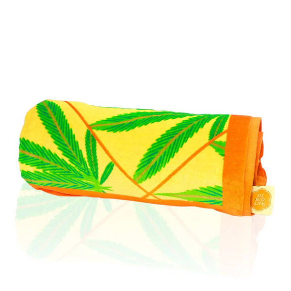 Luxurious big beach towel with bright colors and green bud leaves rolled up.