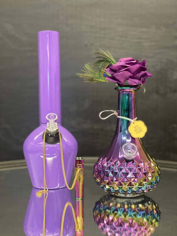 Glossy Purple Steel Chill Pipe and Carnival Glass Iridescent flower vase bong with purple rose flower and peacock feather disguising the mouth piece. Light purple bowl to match. Iridescent metal clipper lighter with gold kasher and chain